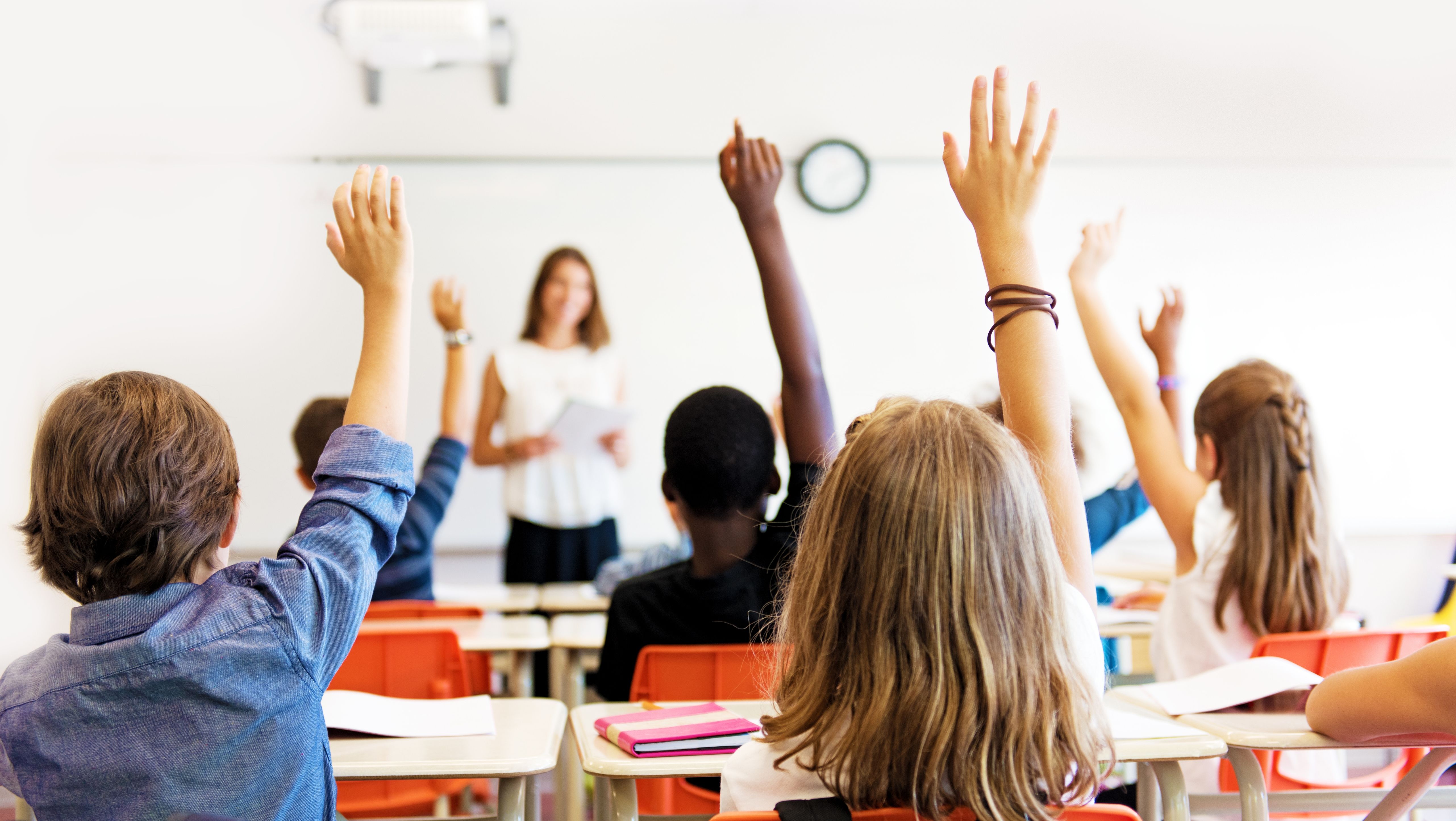 A group of students with raised hands in a classroom